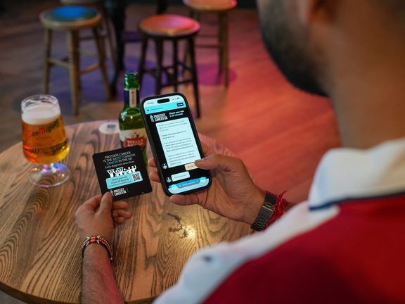 A person using their mobile phone to scan a QR code on a beer mat
