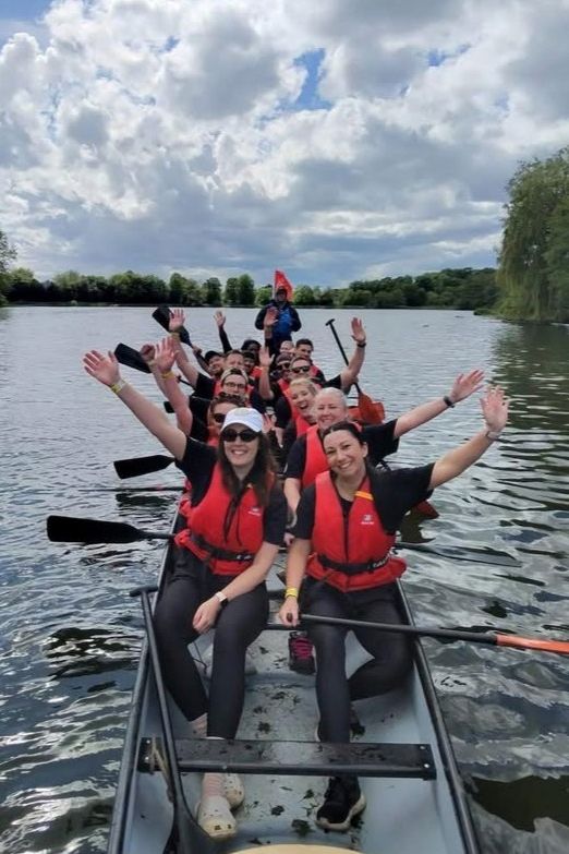 Marston’s Dragon Boat Race team in their boat with hands in the air