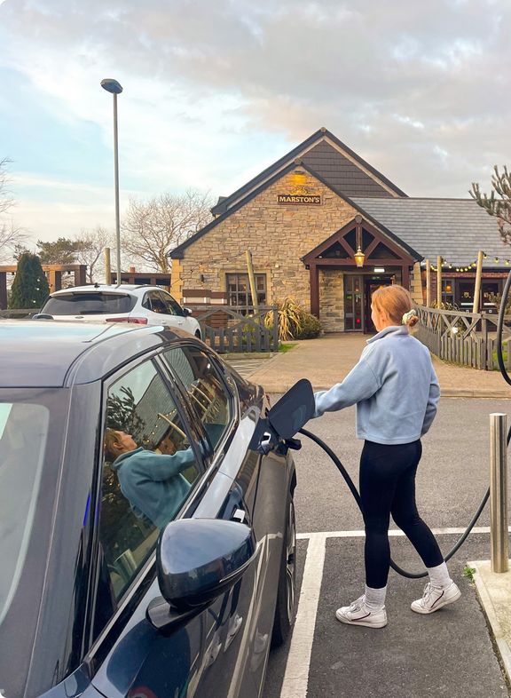 A person plugging a charging cable into an electric car