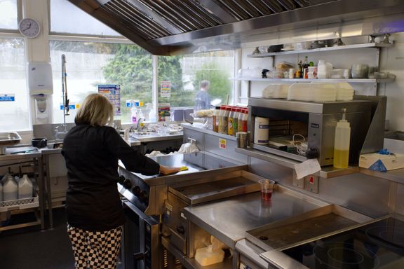 Person wiping a kitchen cooker worktop