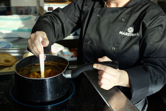 A chef stirring the contents of a pan