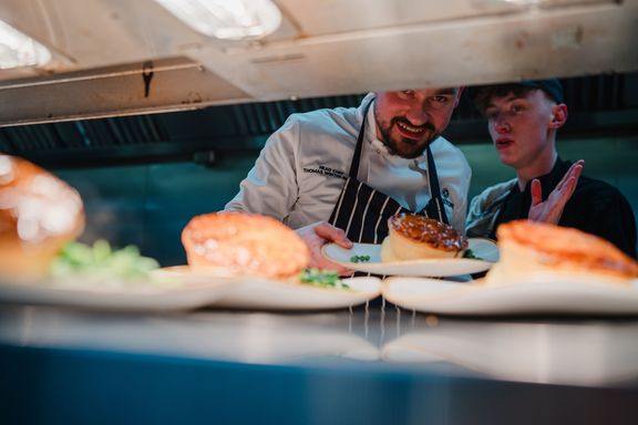 Head chef and chef placing plates with The Best Ever Pub Pie onto the pass