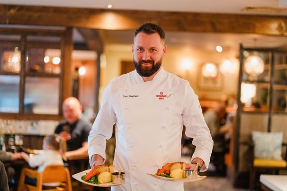Tom Shepherd carrying plates with The Best Ever Pub Pie on
