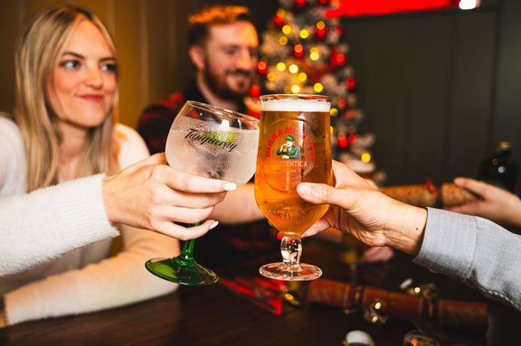 Two glasses being toasted with a woman in the background