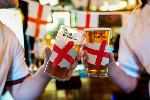 Two people in England football shirts bringing their limited edition glasses together