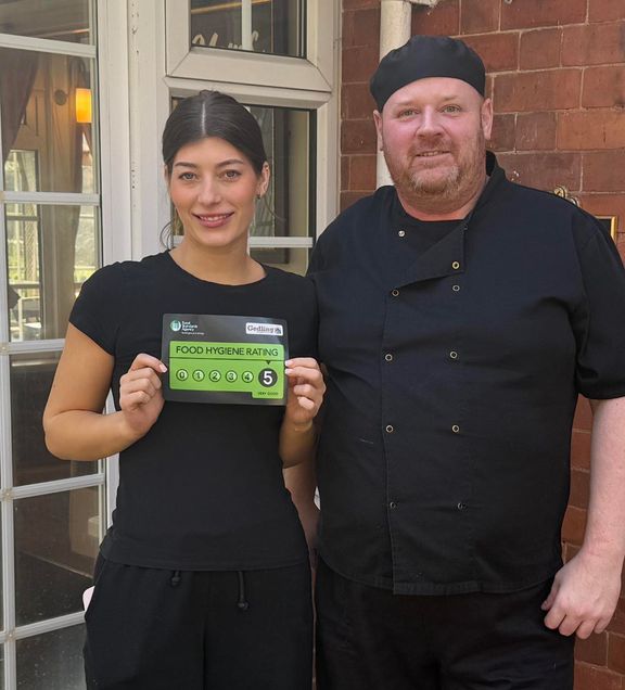 Two pub team members holding up a 5-star Food Hygiene Rating certificate