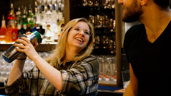 A happy looking team member with a cocktail shaker