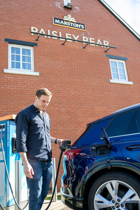 Person holding electric vehicle charging cable outside Paisley Pear pub