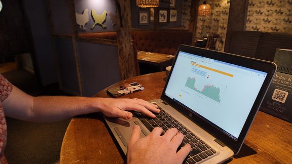 A person viewing an energy monitoring graph on a laptop