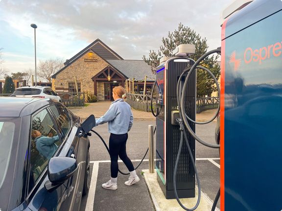 Person plugging a charging lead into an EV car