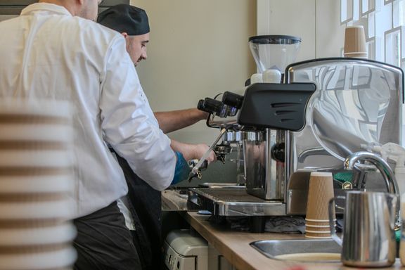 A person in chef's uniform operating a coffee machine