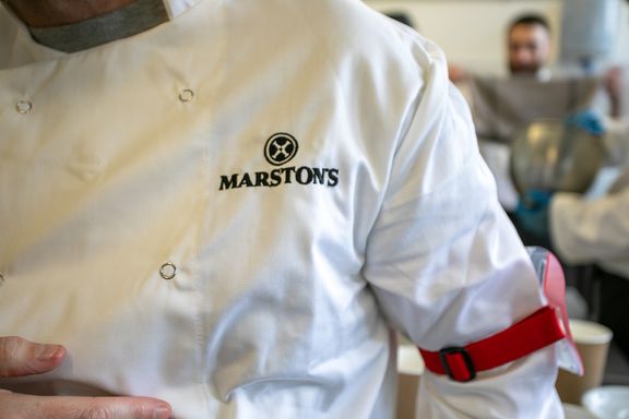 A person wearing a chef's jacket with the Marston's logo