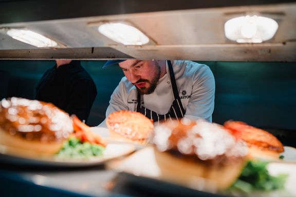 A chef behind the kitchen pass with food in the foreground