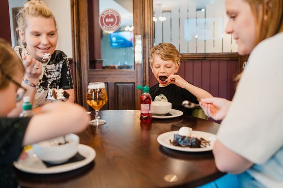 Two women and two children sitting at a table eating desserts